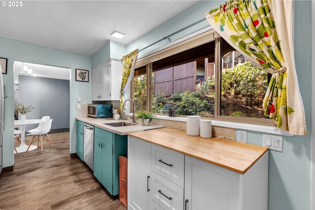 kitchen with stainless steel appliances, butcher block countertops, a sink, decorative backsplash, and light wood finished floors