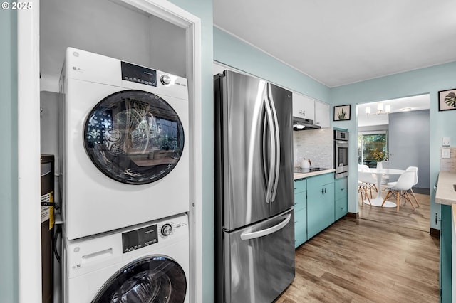 laundry room featuring laundry area, light wood finished floors, and stacked washing maching and dryer