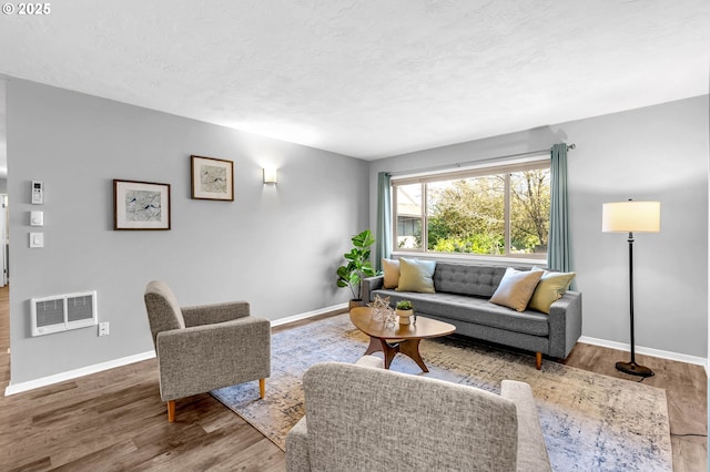 living room featuring a textured ceiling, visible vents, and wood finished floors