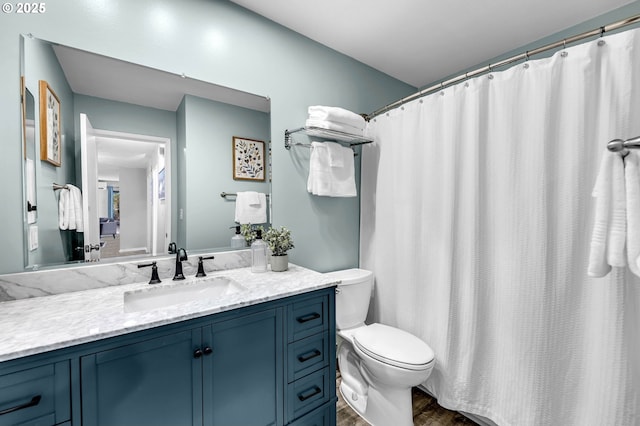 full bath with wood finished floors, vanity, toilet, and curtained shower