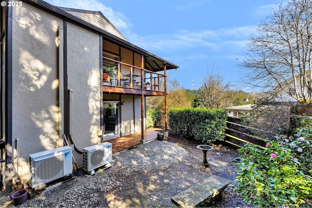 rear view of house featuring a balcony, ac unit, fence, and stucco siding