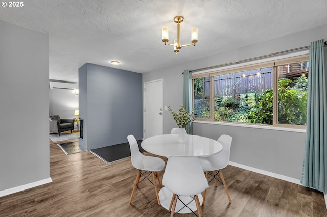 dining room featuring a textured ceiling, plenty of natural light, wood finished floors, and an inviting chandelier