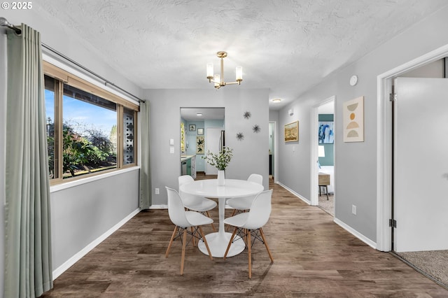 dining area with an inviting chandelier, a textured ceiling, baseboards, and wood finished floors