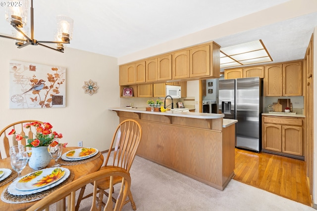 2935 Cedarwood Ct, Albany, OR 97322 - kitchen with stainless steel fridge, white microwave, light countertops, a peninsula, and a chandelier