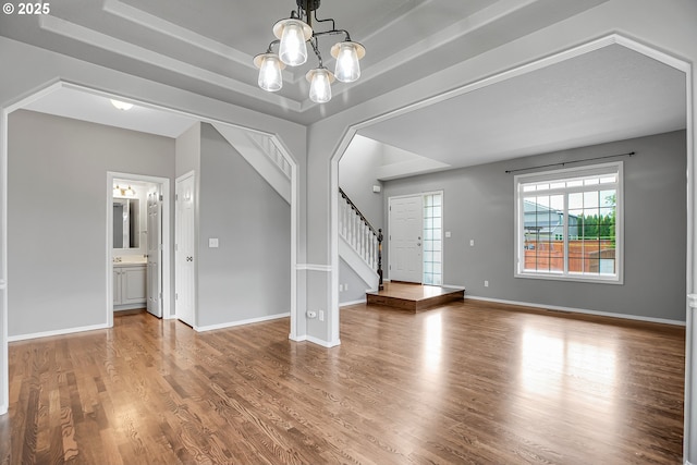 16099 SE Venice Ridge Way, Damascus, OR 97089 - unfurnished living room featuring stairway, wood finished floors, a chandelier, and a tray ceiling