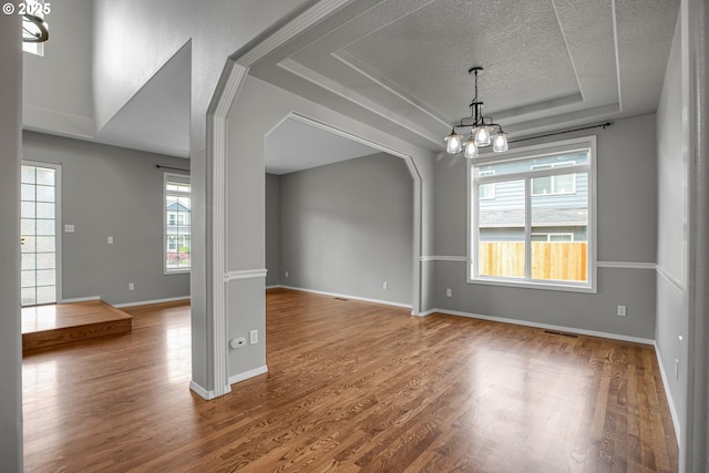 16099 SE Venice Ridge Way, Damascus, OR 97089 - empty room featuring a tray ceiling, a chandelier, healthy amount of natural light, wood finished floors, and a textured ceiling