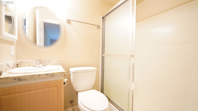 bathroom featuring a stall shower, vanity, and toilet