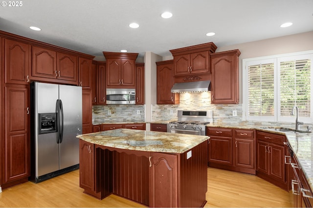1318 NW Slocum Way, Portland, OR 97229 - kitchen with stainless steel appliances, wall chimney exhaust hood, a sink, a center island, and light wood-type flooring