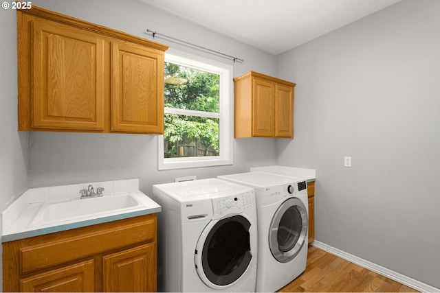 1318 NW Slocum Way, Portland, OR 97229 - laundry area featuring cabinet space, separate washer and dryer, light wood-style flooring, and baseboards