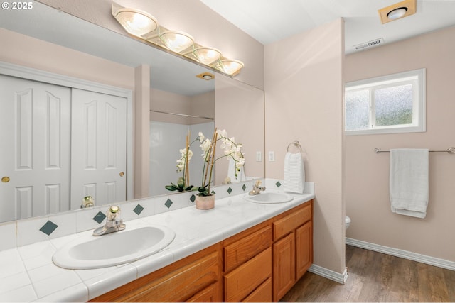 1318 NW Slocum Way, Portland, OR 97229 - bathroom featuring toilet, double vanity, wood finished floors, baseboards, and a shower