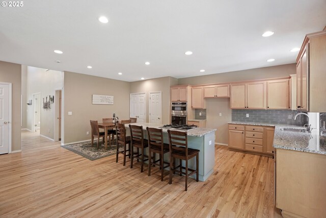 2475 NE 10th Ave, Hillsboro, OR 97124 - kitchen featuring a sink, stainless steel double oven, light brown cabinetry, light wood-style floors, and a kitchen island