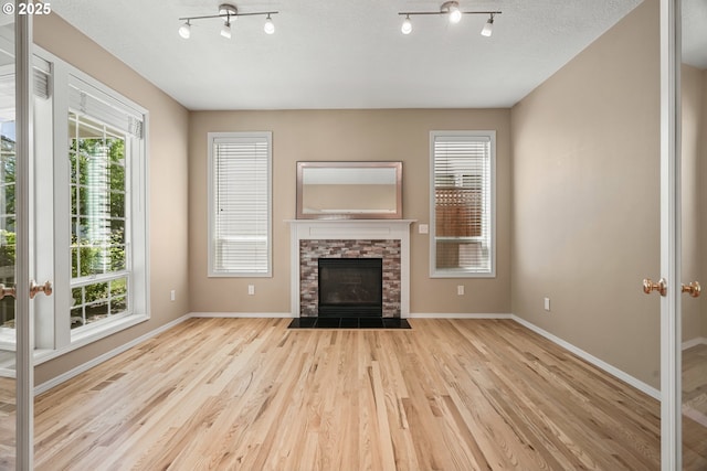 2475 NE 10th Ave, Hillsboro, OR 97124 - unfurnished living room featuring wood finished floors, baseboards, a fireplace, and track lighting
