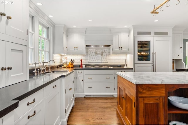 2505 SW Hillcrest Dr, Portland, OR 97201 - kitchen featuring a sink, tasteful backsplash, wood finished floors, white cabinetry, and ornamental molding