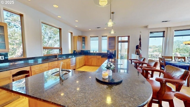 94414 Tom Cat Hill Rd, Gold Beach, OR 97444 - kitchen with plenty of natural light, dark stone counters, glass insert cabinets, a large island with sink, and recessed lighting