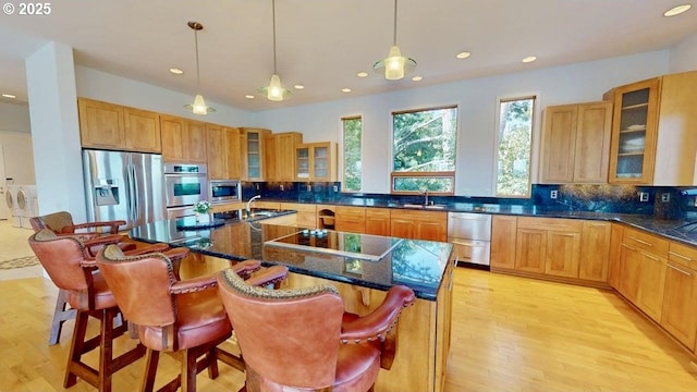 94414 Tom Cat Hill Rd, Gold Beach, OR 97444 - kitchen with stainless steel appliances, recessed lighting, backsplash, washing machine and clothes dryer, and an island with sink
