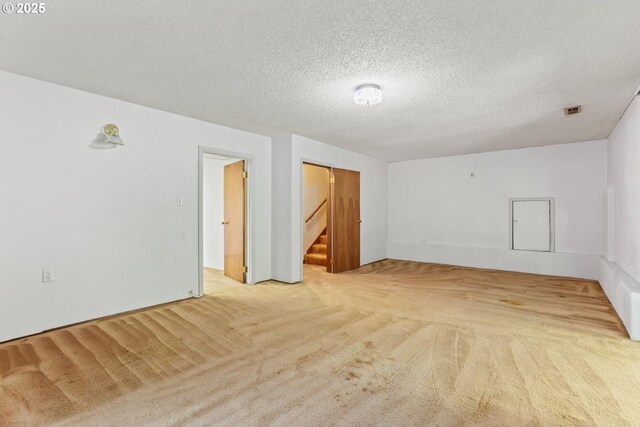 carpeted spare room featuring stairs and a textured ceiling