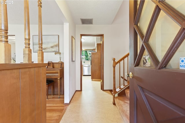 hallway with stairway, baseboards, light wood-type flooring, and visible vents