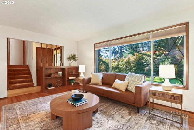 living room with visible vents, stairs, and wood finished floors