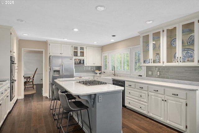 kitchen featuring stainless steel appliances, dark wood-style floors, a breakfast bar area, a center island, and recessed lighting
