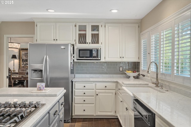 kitchen with stainless steel appliances, a sink, light stone counters, white cabinets, and recessed lighting