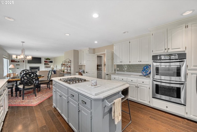 kitchen featuring stainless steel appliances, a kitchen island, dark wood-type flooring, white cabinets, and recessed lighting