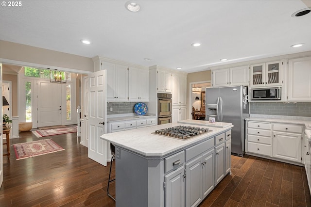 kitchen featuring appliances with stainless steel finishes, dark wood-style floors, light countertops, a kitchen island, and white cabinetry