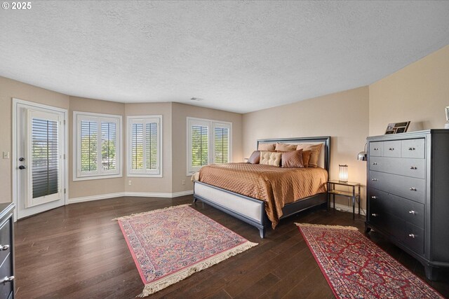 bedroom featuring dark wood-type flooring, a textured ceiling, baseboards, and access to exterior
