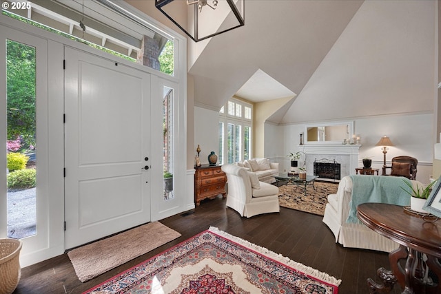 entryway with dark wood-style flooring, a fireplace, and a towering ceiling