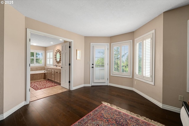foyer entrance featuring baseboards, hardwood / wood-style floors, and a textured ceiling