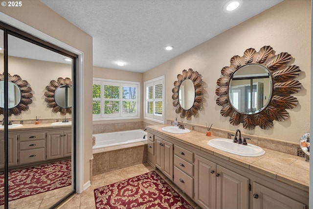 bathroom featuring a garden tub, double vanity, tile patterned flooring, recessed lighting, and a textured ceiling