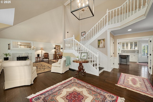 living area featuring a high ceiling, hardwood / wood-style floors, stairway, a fireplace, and crown molding