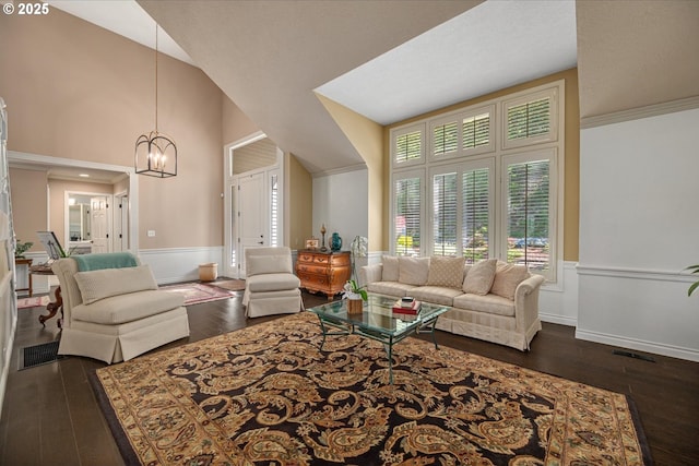living area featuring dark wood-style flooring, a chandelier, a wainscoted wall, baseboards, and high vaulted ceiling