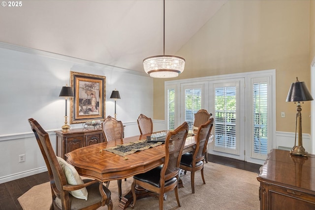 dining area featuring high vaulted ceiling, wood finished floors, a chandelier, ornamental molding, and baseboards