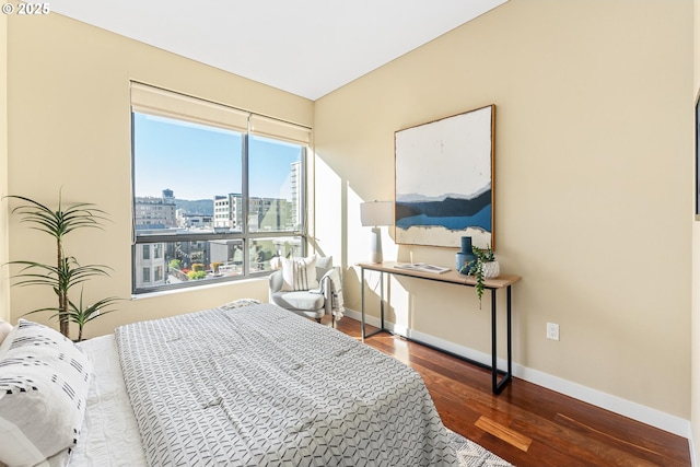 bedroom featuring a city view, baseboards, and wood finished floors