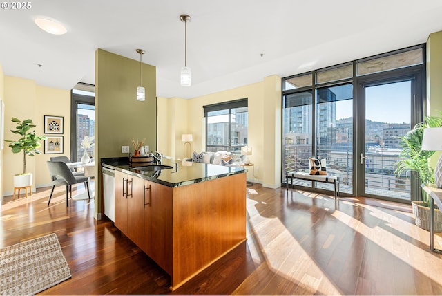 kitchen featuring a peninsula, a sink, dishwasher, dark countertops, and dark wood finished floors