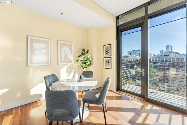 dining room featuring a healthy amount of sunlight, expansive windows, a view of city, and wood finished floors