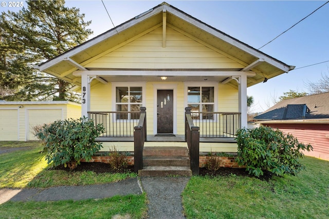 bungalow featuring a garage, a front lawn, and covered porch