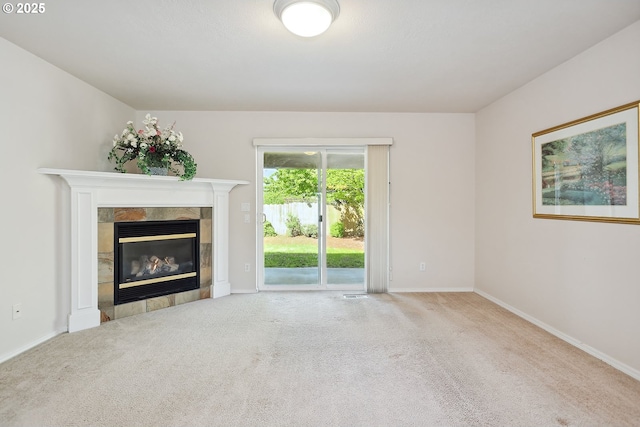 unfurnished living room featuring a tile fireplace, carpet floors, and baseboards