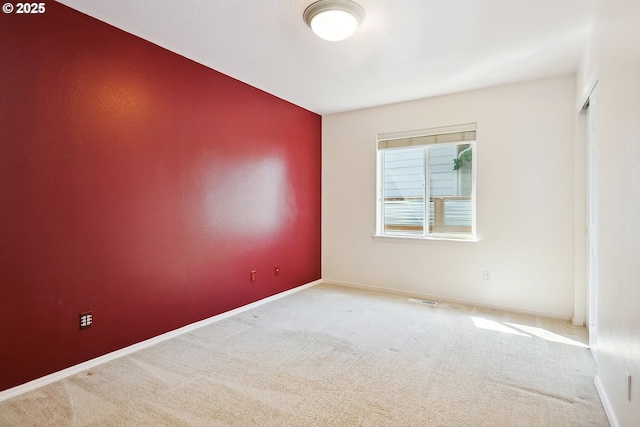carpeted spare room with visible vents and baseboards