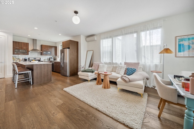 living area with a wall mounted AC, recessed lighting, and wood finished floors