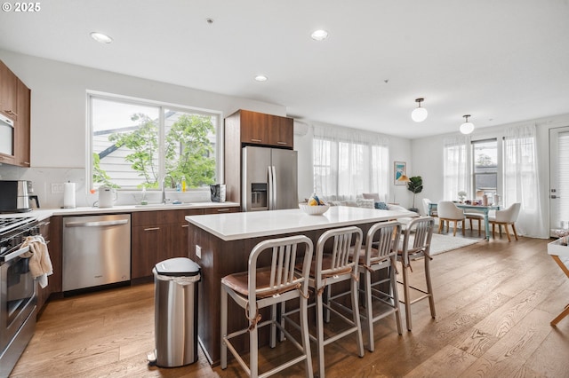 kitchen with a sink, appliances with stainless steel finishes, a center island, and light wood-style flooring