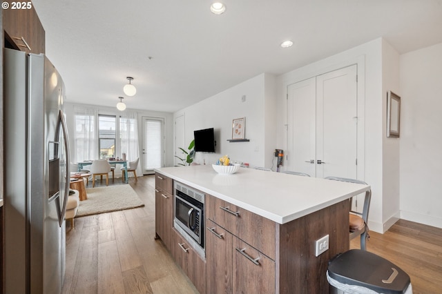 kitchen with a breakfast bar area, appliances with stainless steel finishes, modern cabinets, a center island, and light wood-style flooring