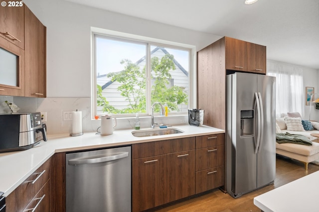 kitchen featuring a sink, plenty of natural light, stainless steel appliances, and light wood-style flooring