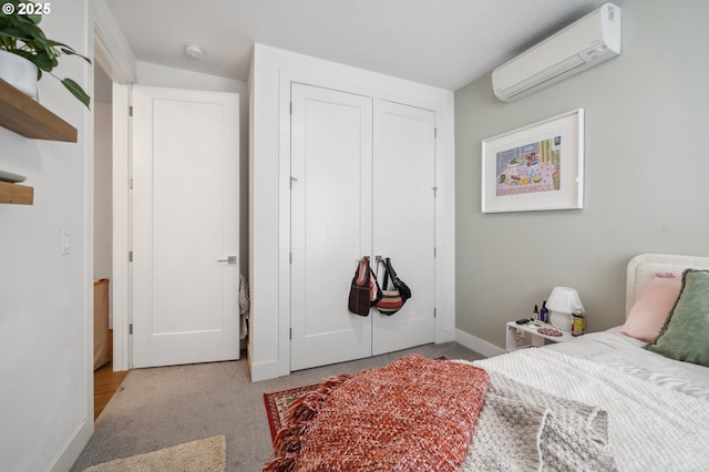 bedroom with baseboards, carpet floors, a wall unit AC, and a closet