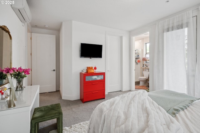 carpeted bedroom with baseboards, ensuite bathroom, and a wall mounted air conditioner