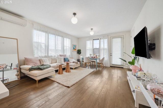living area with a wall unit AC and hardwood / wood-style floors