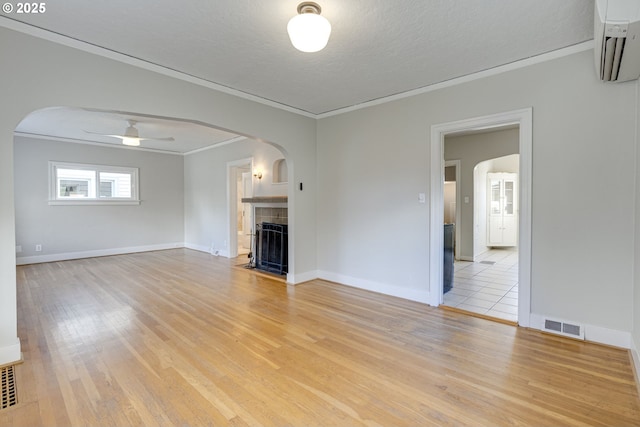 unfurnished living room with crown molding, a textured ceiling, ceiling fan, and light hardwood / wood-style floors