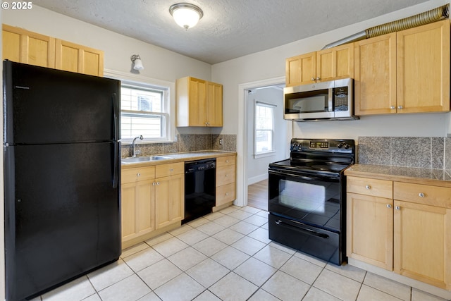 kitchen featuring a wealth of natural light, light brown cabinetry, sink, and black appliances