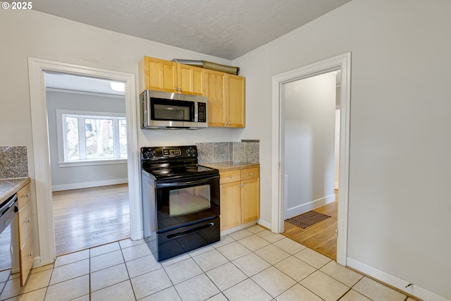 kitchen featuring stainless steel appliances, light brown cabinetry, a textured ceiling, and light tile patterned floors