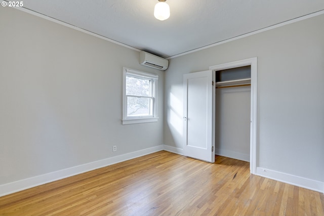 unfurnished bedroom featuring a closet, a wall unit AC, and light hardwood / wood-style floors